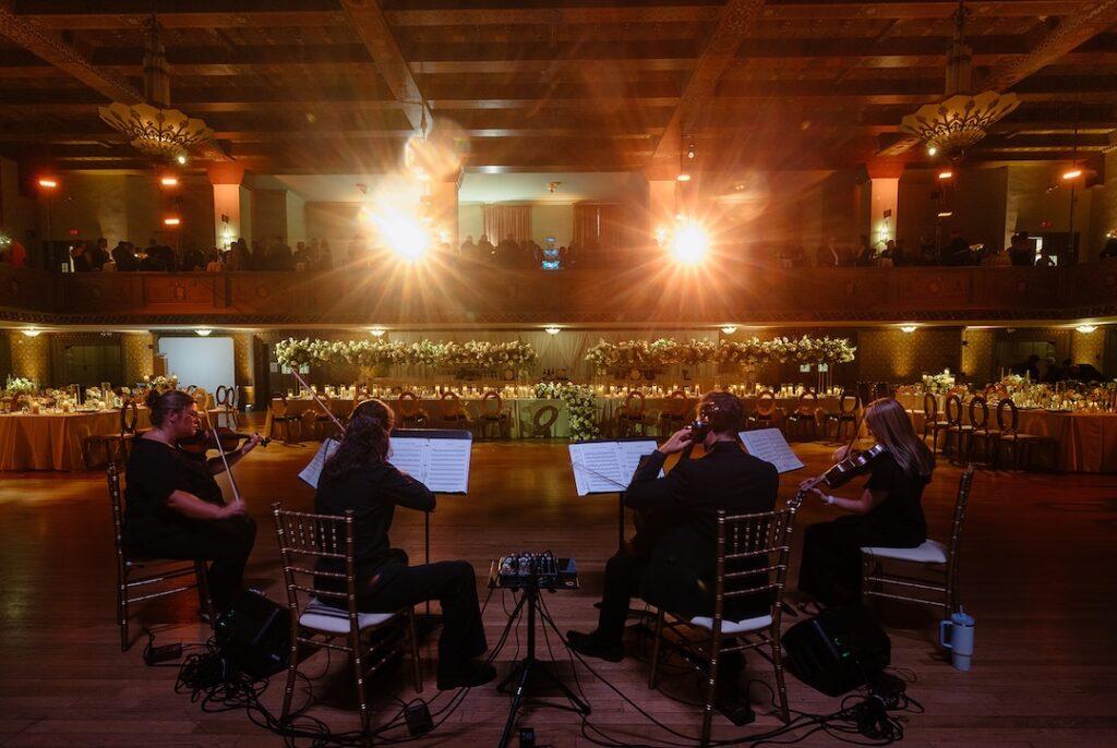 String quartet performing at an elegant evening event with warm lighting and floral decor.
