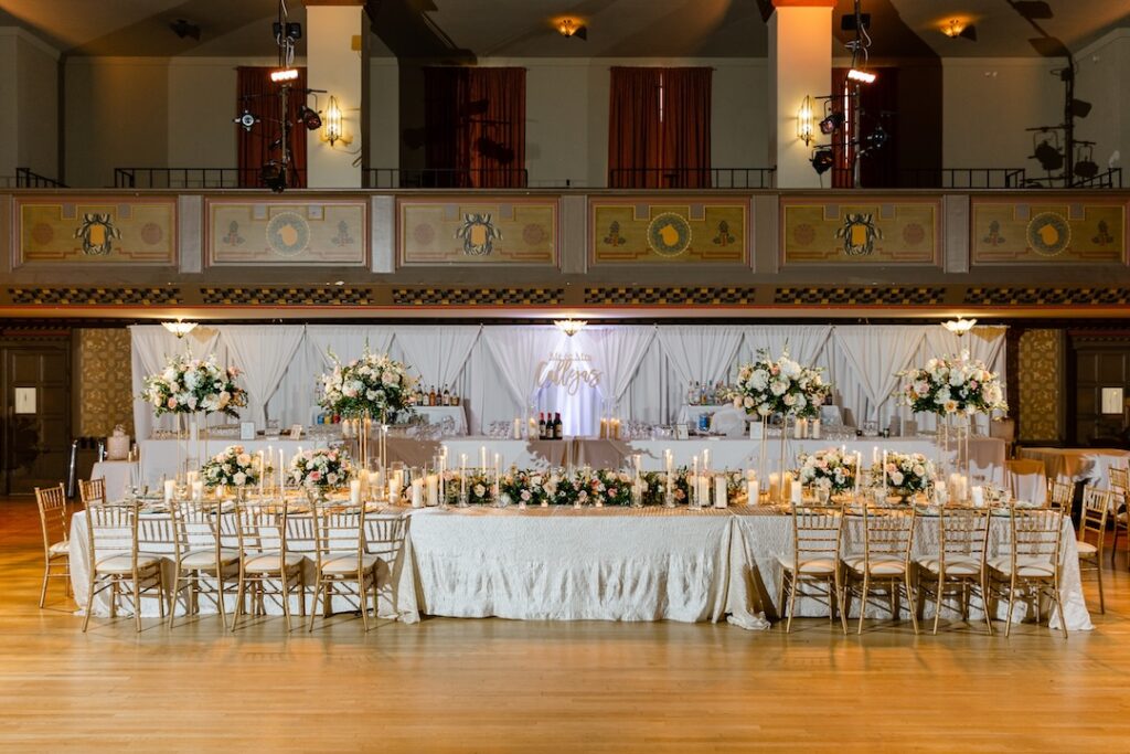 Elegant wedding reception with floral centerpieces and candles on a beautifully set long table.