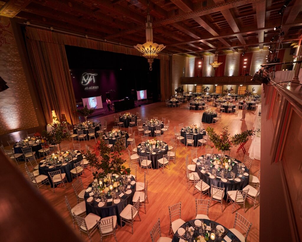 Elegant ballroom event setup with round tables, floral centerpieces, and dim lighting. Ideal for weddings or galas.