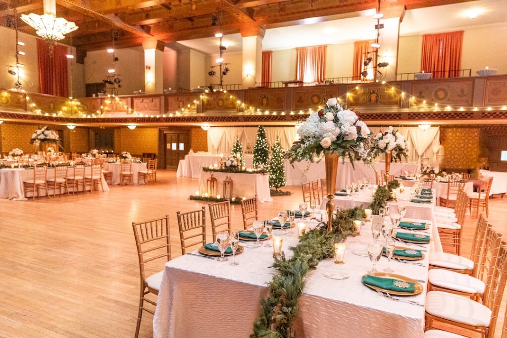 Elegant banquet hall decorated for a glamorous wedding reception with floral centerpieces and warm lighting.