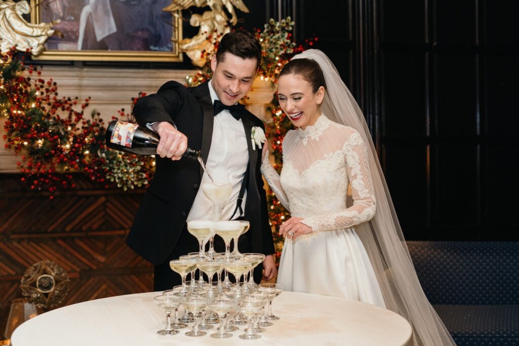 Bride and groom pouring champagne into a tower at their wedding reception.